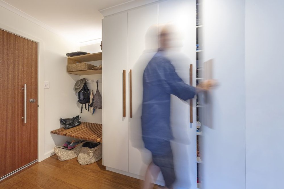 Réalisation d'un petit hall d'entrée design avec un mur blanc, parquet en bambou, une porte simple, une porte en bois brun et un sol marron.