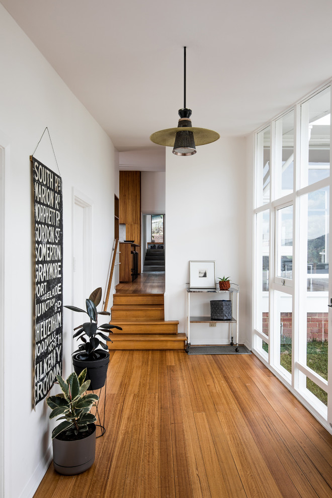 Moderner Eingang mit Korridor, weißer Wandfarbe, braunem Holzboden und braunem Boden in Hobart