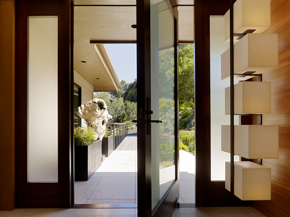 Ispirazione per un piccolo corridoio minimal con pareti marroni, una porta a pivot, una porta in vetro e pavimento beige
