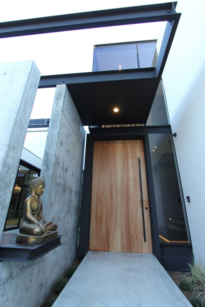 Cette photo montre un hall d'entrée tendance de taille moyenne avec un mur blanc, parquet clair, une porte pivot, une porte en bois brun et un sol gris.