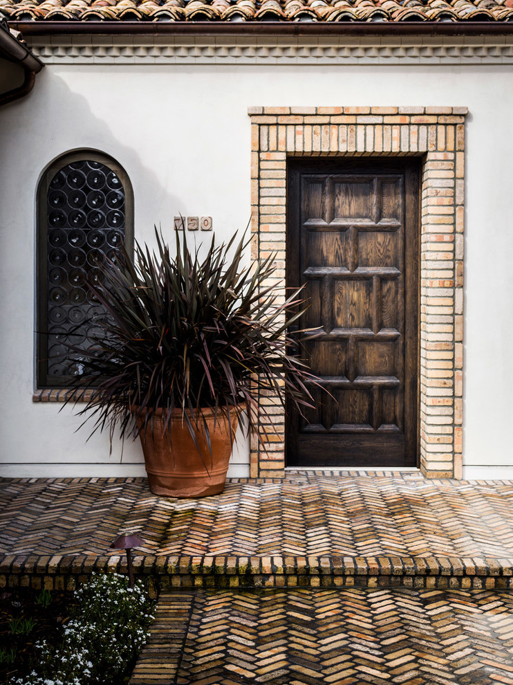 Mittelgroße Mediterrane Haustür mit weißer Wandfarbe, Backsteinboden, Einzeltür, dunkler Holzhaustür und braunem Boden in Santa Barbara