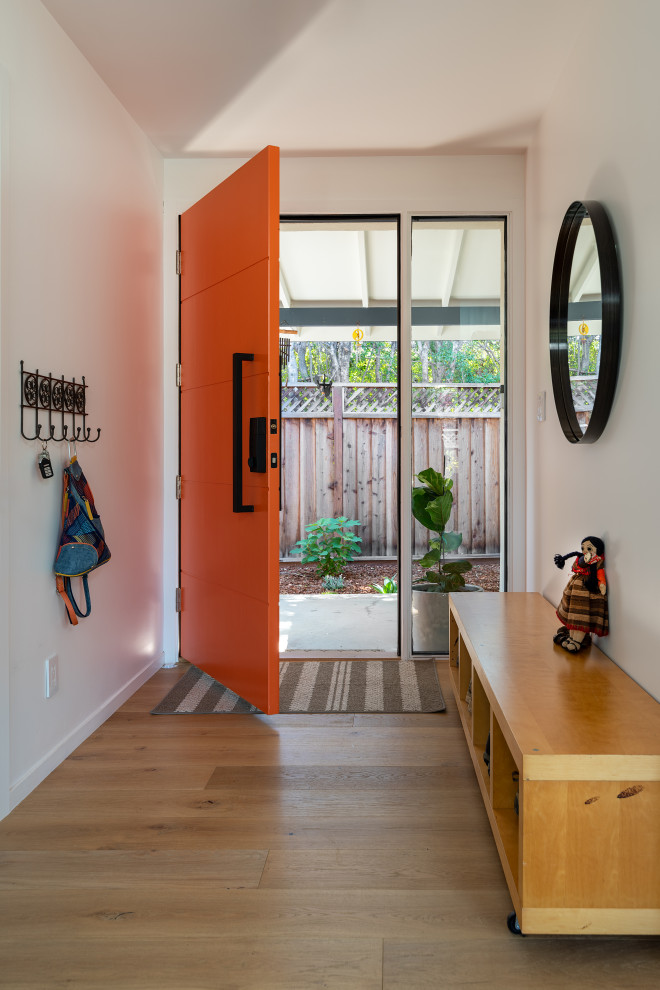 Imagen de distribuidor actual de tamaño medio con paredes blancas, suelo de madera clara, puerta simple, puerta naranja y suelo beige