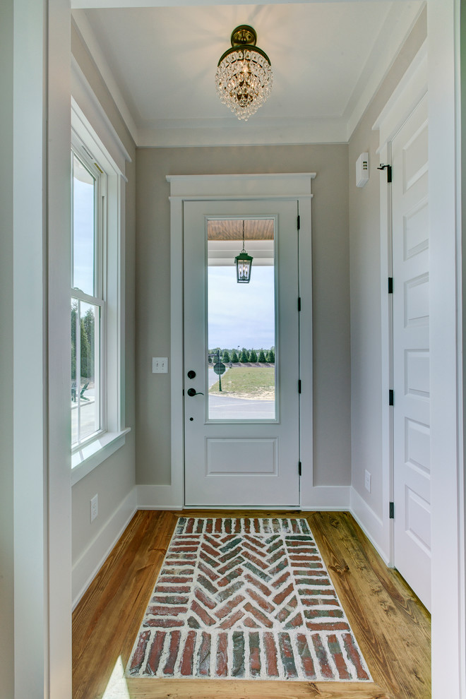 Стильный дизайн: маленькое фойе в стиле кантри с серыми стенами, кирпичным полом, одностворчатой входной дверью, белой входной дверью и красным полом для на участке и в саду - последний тренд