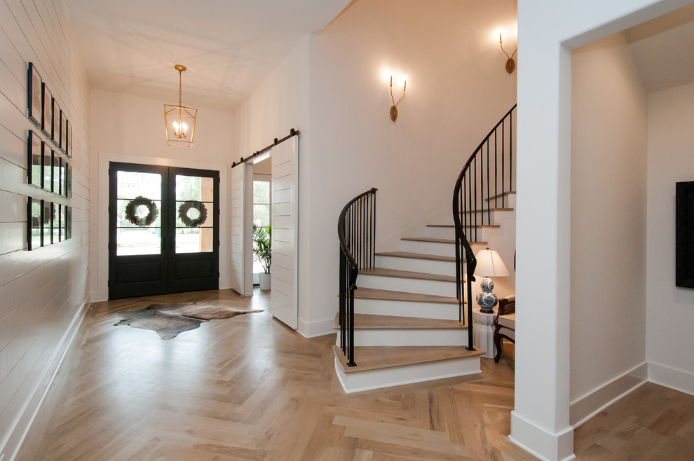 Large country foyer in Houston with white walls, light hardwood flooring, a double front door, a black front door, beige floors and feature lighting.
