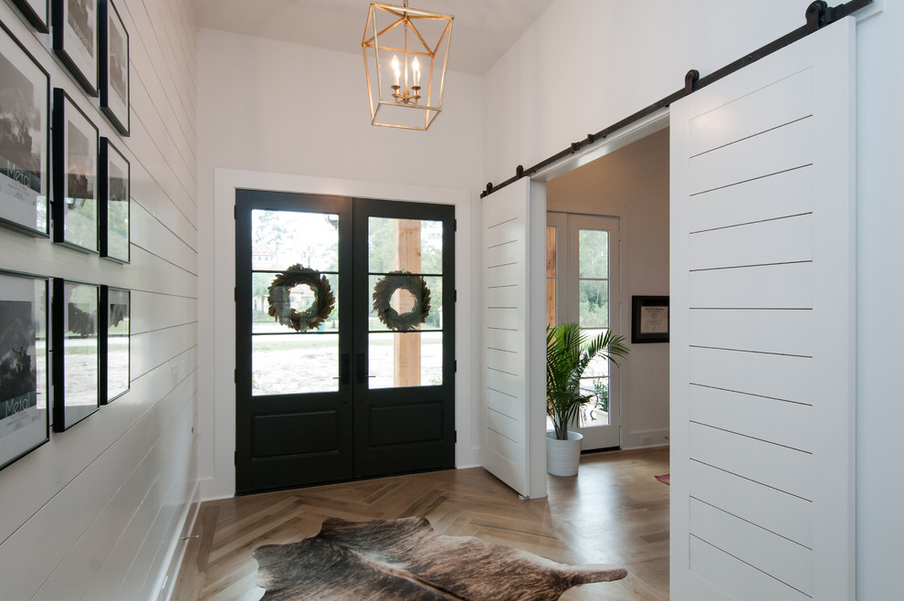 Großes Landhaus Foyer mit weißer Wandfarbe, hellem Holzboden, Doppeltür, schwarzer Haustür und beigem Boden in Houston
