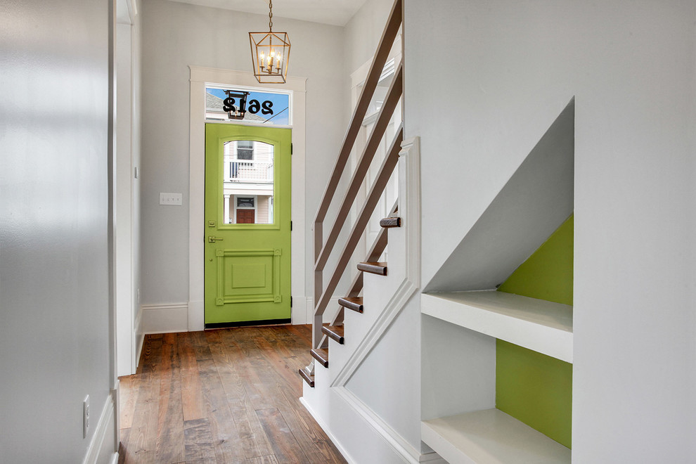 Ispirazione per un corridoio tradizionale di medie dimensioni con pareti grigie, pavimento in legno massello medio, una porta singola e una porta verde