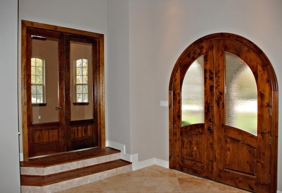 Entryway - large mediterranean travertine floor entryway idea in Houston with beige walls and a dark wood front door