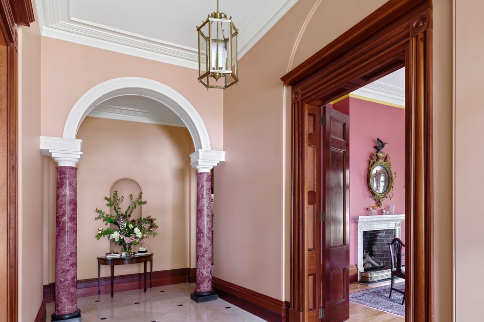 На фото: большая узкая прихожая в классическом стиле с розовыми стенами, мраморным полом, одностворчатой входной дверью и белой входной дверью