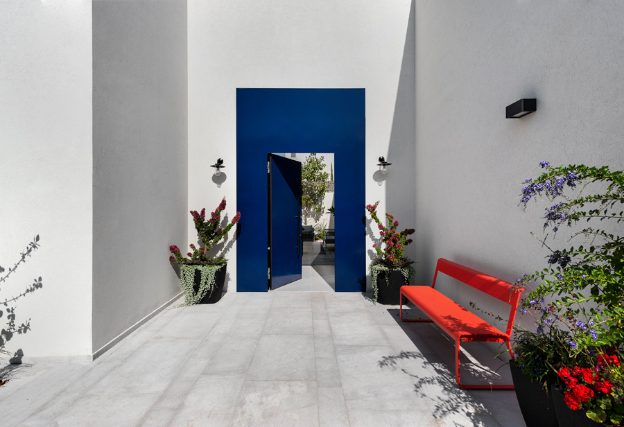 Réalisation d'une grande porte d'entrée minimaliste avec un mur blanc, un sol en calcaire, une porte simple, une porte bleue et un sol gris.