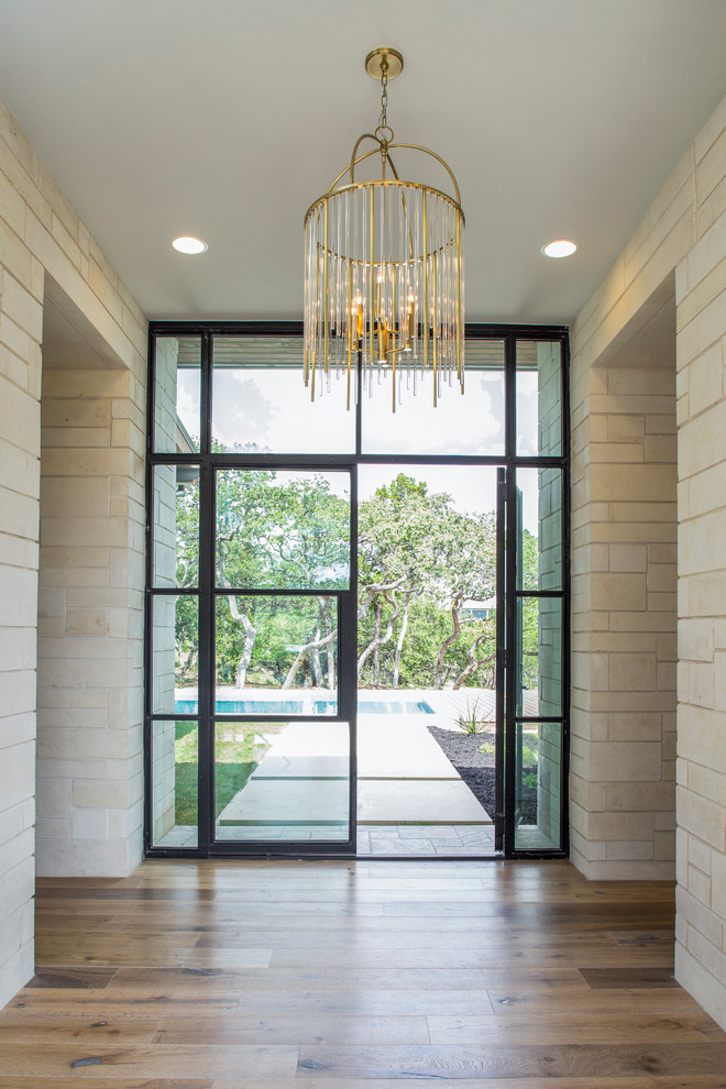 Cette image montre un hall d'entrée traditionnel avec un mur beige, un sol en bois brun, une porte double et une porte en verre.