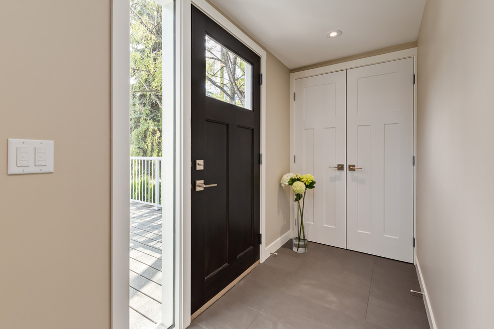 This is an example of a medium sized contemporary front door in Calgary with beige walls, porcelain flooring, a single front door, a dark wood front door and brown floors.