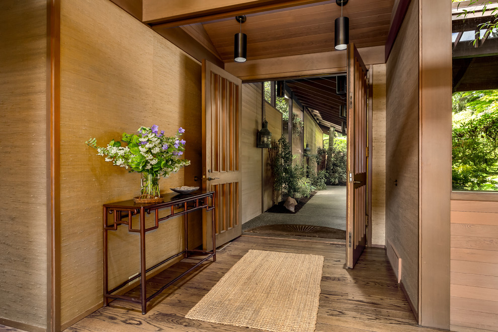 Réalisation d'un très grand hall d'entrée asiatique avec un sol en bois brun, une porte double et une porte en bois brun.