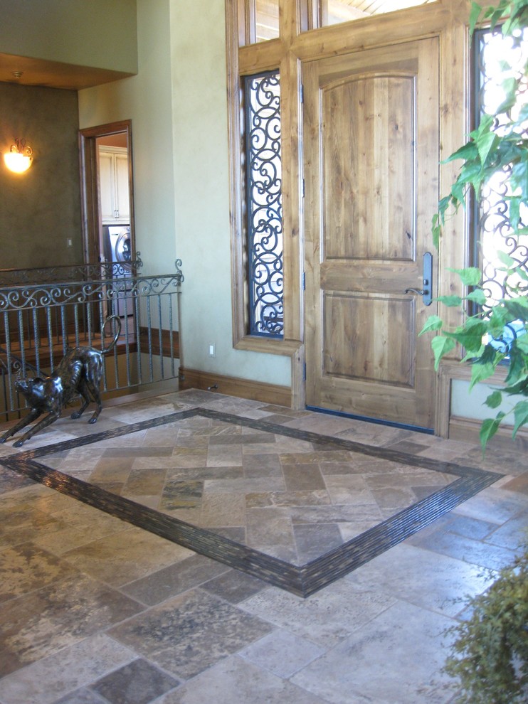 На фото: фойе в классическом стиле с бежевыми стенами, полом из сланца и входной дверью из дерева среднего тона с
