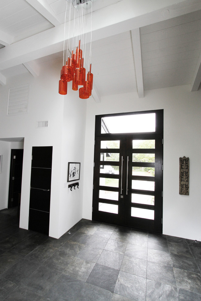 Foto di un ampio ingresso moderno con pareti bianche, pavimento in ardesia, una porta a due ante e una porta in legno scuro