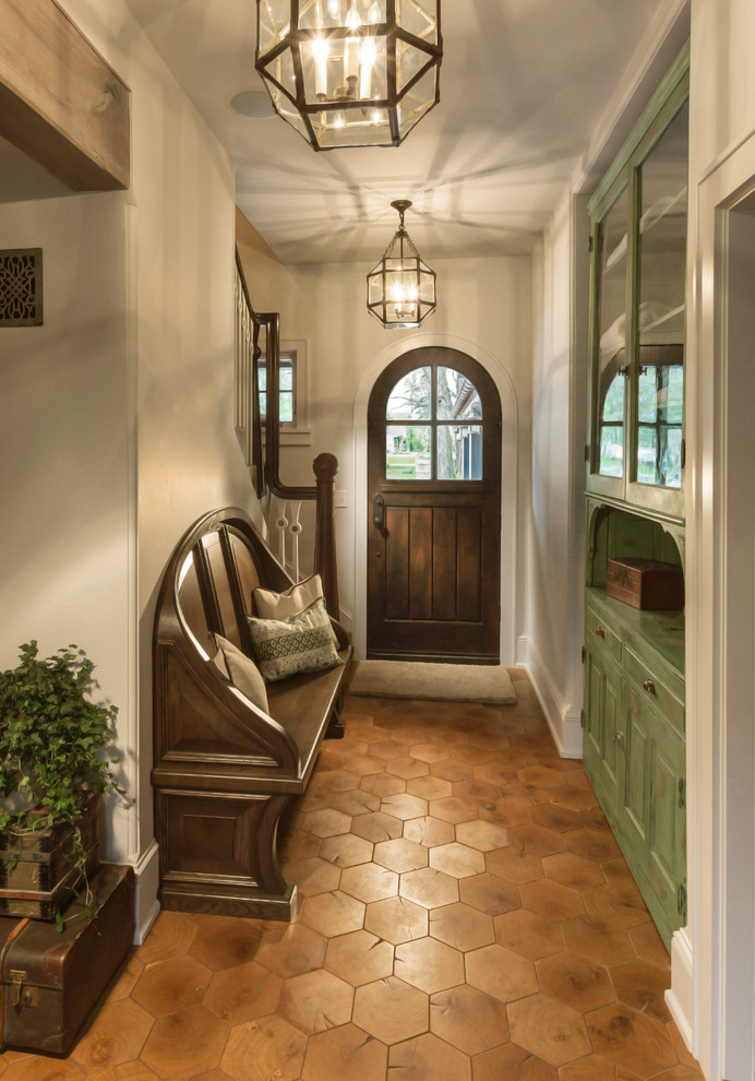 Cette image montre une entrée traditionnelle de taille moyenne avec un couloir, un mur beige, une porte simple, une porte en bois foncé et un sol en bois brun.