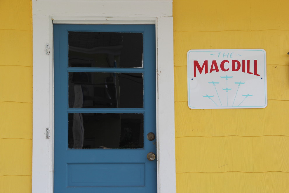タンパにある低価格の小さなビーチスタイルのおしゃれな玄関ドア (黄色い壁、コンクリートの床、青いドア) の写真