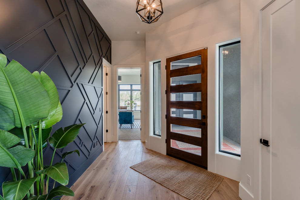 Idées déco pour un hall d'entrée contemporain avec un mur noir, parquet clair, une porte simple, une porte en bois foncé et un sol marron.