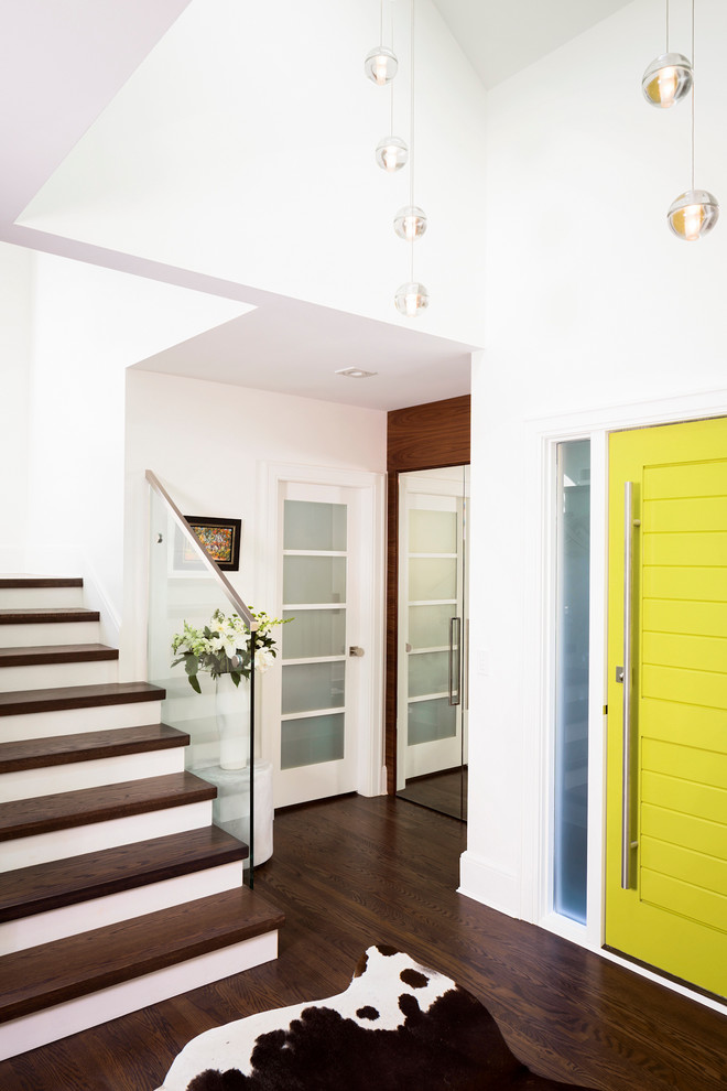 Esempio di un ingresso o corridoio design con pareti bianche, parquet scuro, una porta singola e una porta gialla