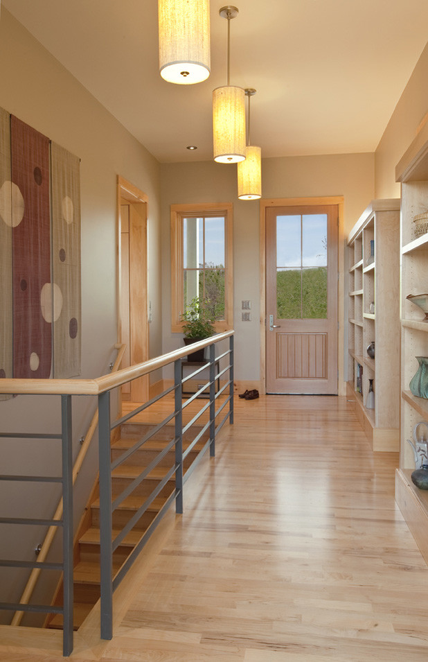 Ispirazione per un corridoio minimalista di medie dimensioni con pareti beige, parquet chiaro, una porta in legno chiaro e una porta singola