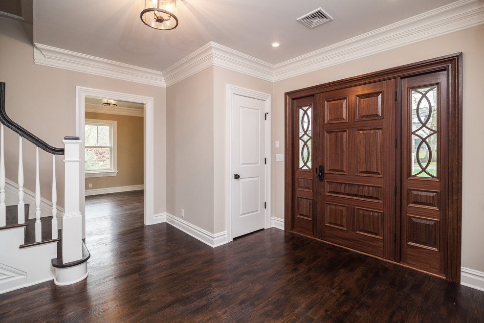 Cette image montre un hall d'entrée design de taille moyenne avec un mur beige, parquet foncé, une porte simple et une porte en bois foncé.