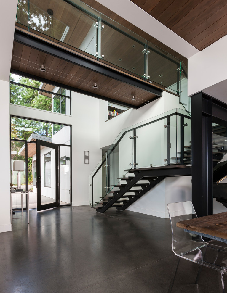 Photo of a contemporary foyer in Seattle with white walls, a single front door, a black front door, concrete flooring and grey floors.