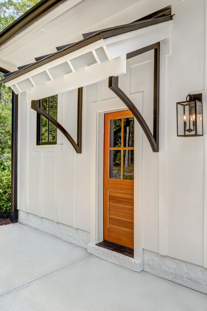 Diseño de vestíbulo de estilo de casa de campo grande con paredes blancas, puerta simple y puerta de madera clara