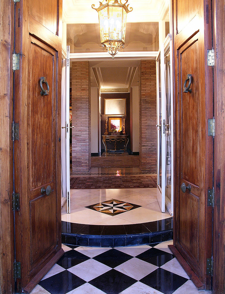 Modelo de vestíbulo tradicional grande con paredes marrones, puerta doble y puerta de madera en tonos medios
