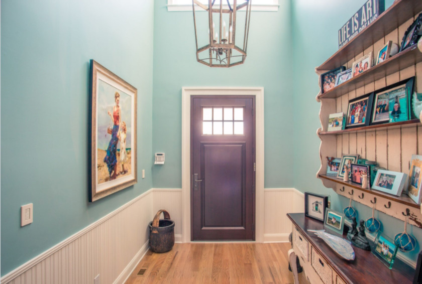 This is an example of a medium sized coastal hallway in Orange County with blue walls, light hardwood flooring, a single front door and a dark wood front door.