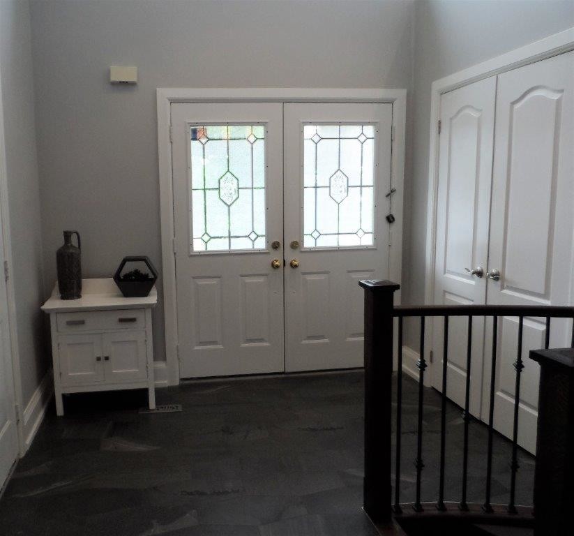Idée de décoration pour un petit hall d'entrée tradition avec un mur gris, un sol en carrelage de porcelaine, une porte double, une porte blanche et un sol noir.