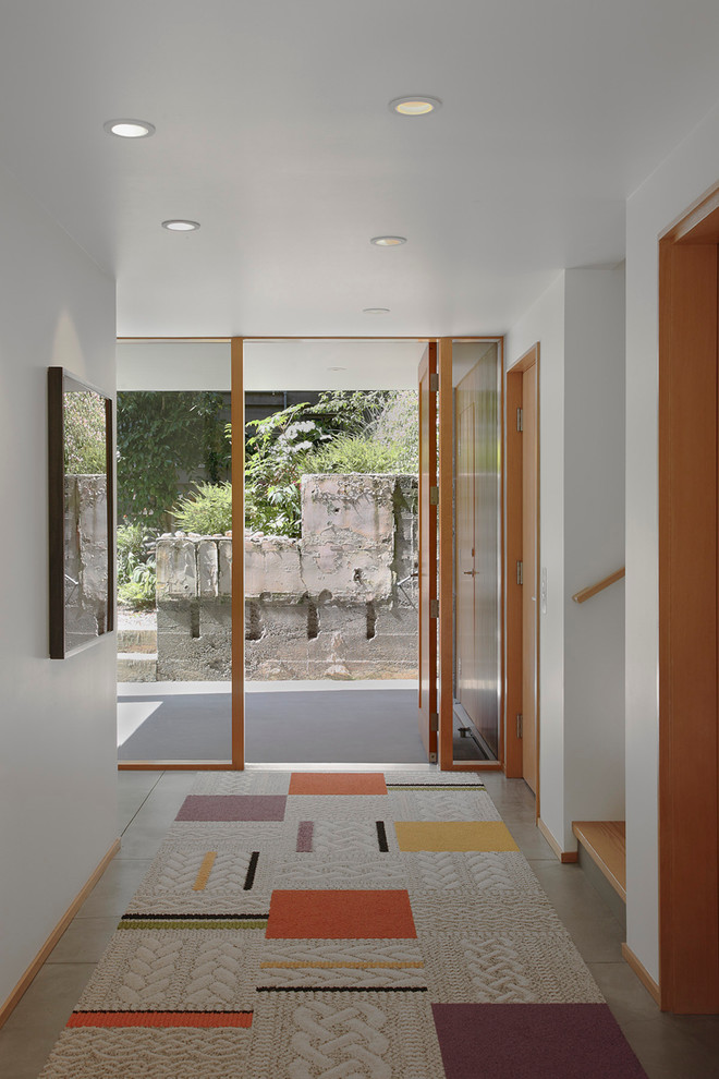 Réalisation d'une entrée minimaliste avec sol en béton ciré et un mur blanc.