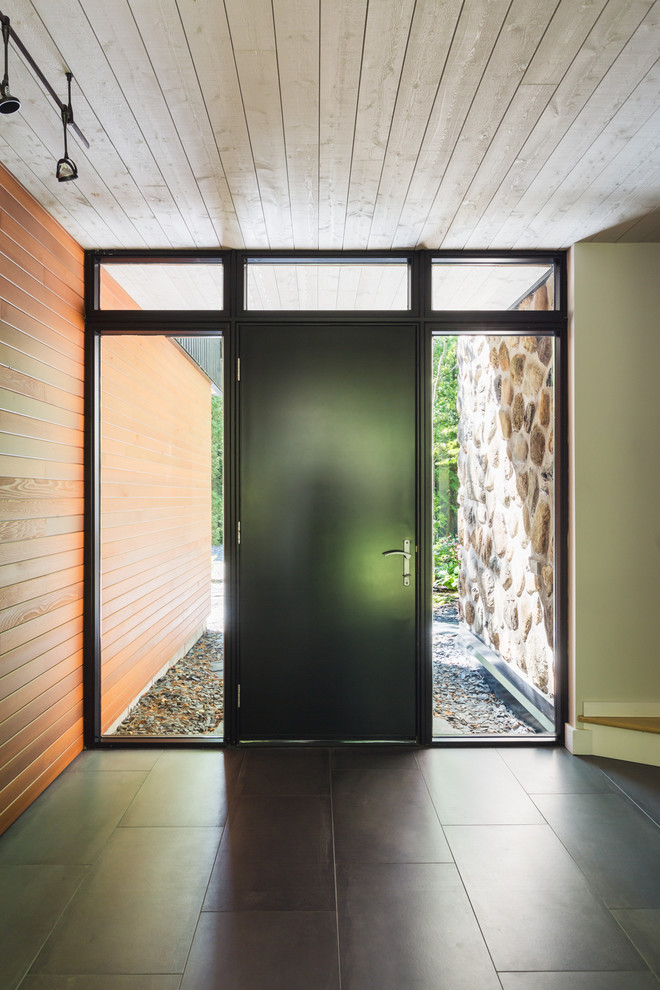 На фото: огромное фойе в современном стиле с белыми стенами, полом из керамической плитки, одностворчатой входной дверью и черной входной дверью