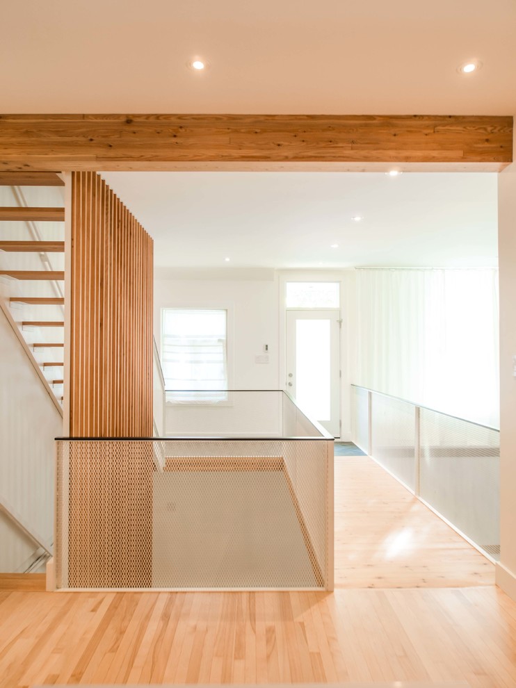 Photo of a medium sized contemporary foyer in Montreal with white walls, light hardwood flooring, a single front door, a white front door and brown floors.