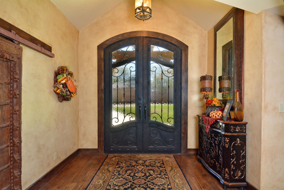 Diseño de puerta principal rústica con paredes beige, suelo de madera en tonos medios, puerta doble y puerta metalizada