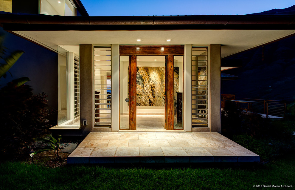 ハワイにあるトロピカルスタイルのおしゃれな玄関 (白い壁、トラバーチンの床、木目調のドア) の写真