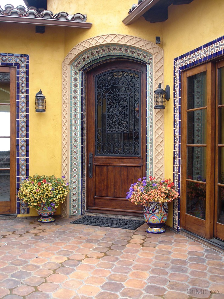Inspiration pour une porte d'entrée bohème avec un mur jaune, tomettes au sol, une porte simple et une porte en bois brun.