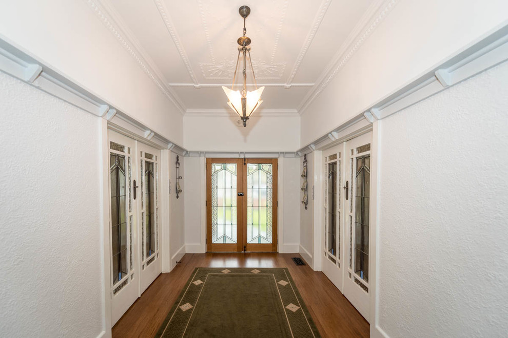 Idee per un ingresso stile americano di medie dimensioni con pareti bianche, parquet scuro, una porta a due ante, una porta in legno scuro e pavimento marrone