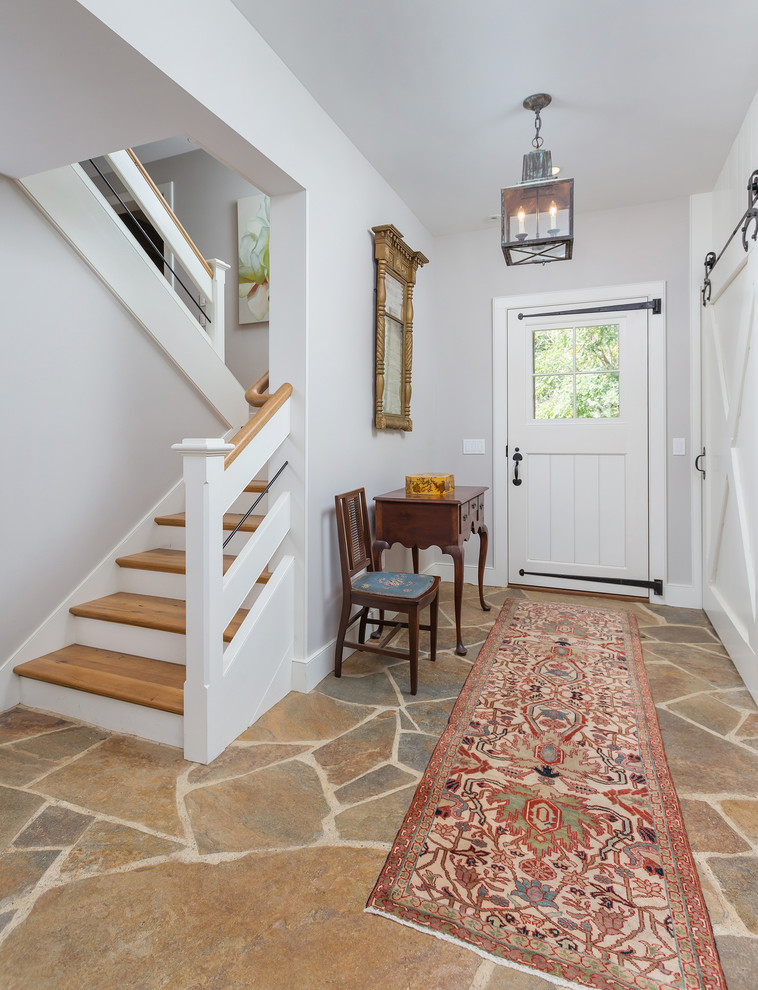 На фото: узкая прихожая в стиле кантри с серыми стенами, одностворчатой входной дверью, белой входной дверью и разноцветным полом с