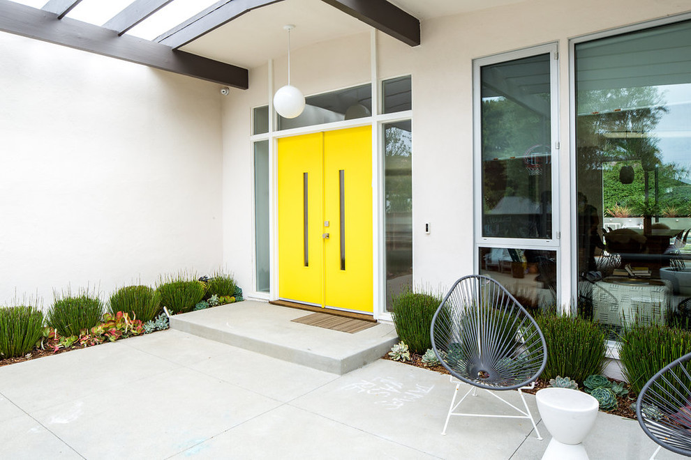 Свежая идея для дизайна: входная дверь в стиле ретро с белыми стенами, бетонным полом, двустворчатой входной дверью, желтой входной дверью и серым полом - отличное фото интерьера