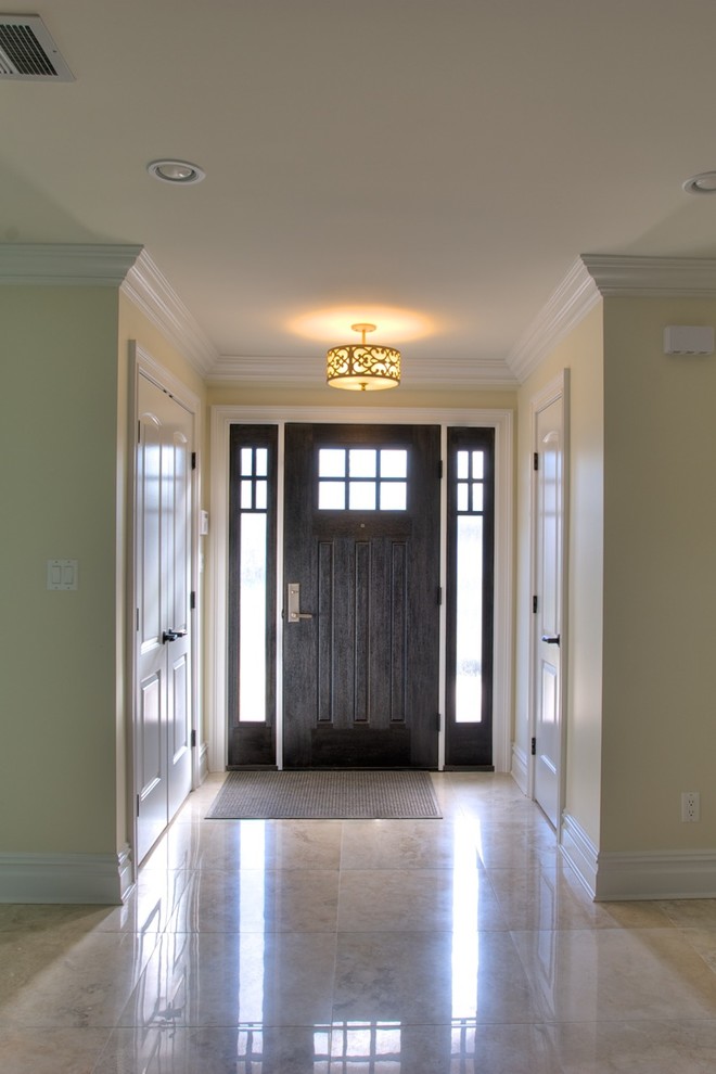 Стильный дизайн: большая входная дверь в классическом стиле с желтыми стенами, полом из керамогранита, одностворчатой входной дверью, входной дверью из темного дерева и бежевым полом - последний тренд