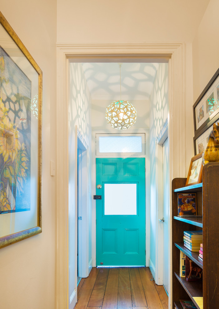Immagine di un piccolo corridoio stile marinaro con pareti bianche, pavimento in legno massello medio, una porta singola e una porta blu
