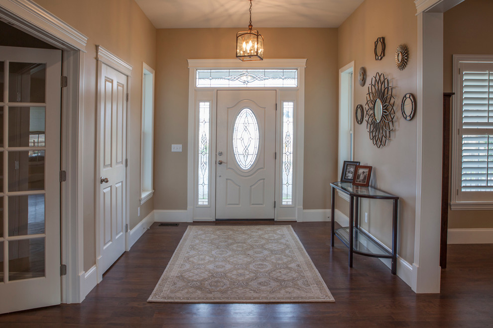 This is an example of a medium sized traditional front door in Denver with beige walls, medium hardwood flooring, a pivot front door and a white front door.