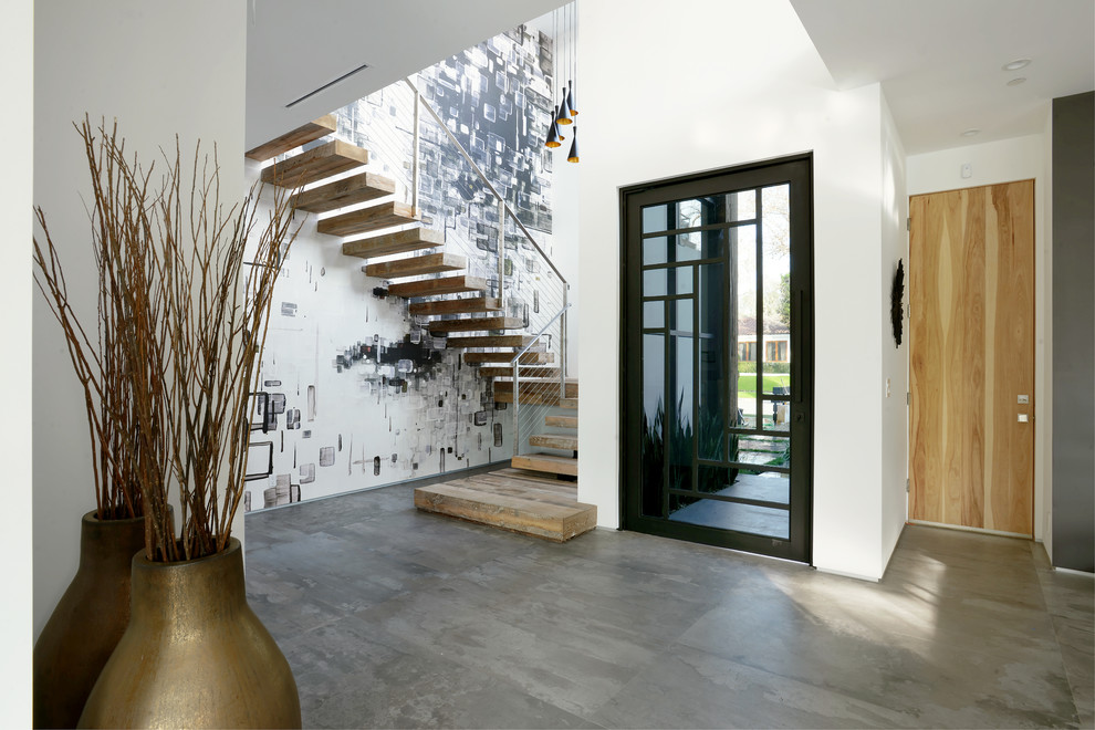 Immagine di un ingresso design di medie dimensioni con pareti bianche, pavimento in cemento, una porta singola e una porta in vetro
