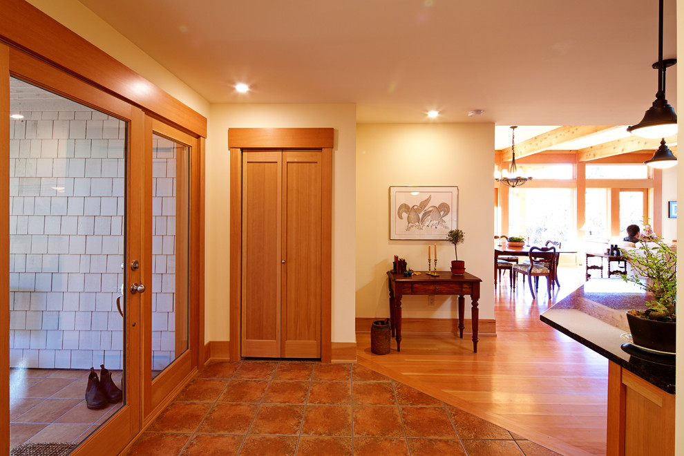 Réalisation d'une grande porte d'entrée craftsman avec un mur blanc, tomettes au sol, une porte simple et une porte en bois brun.