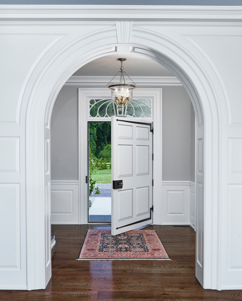 Inspiration pour un hall d'entrée traditionnel avec un mur gris, un sol en bois brun, une porte simple et une porte blanche.
