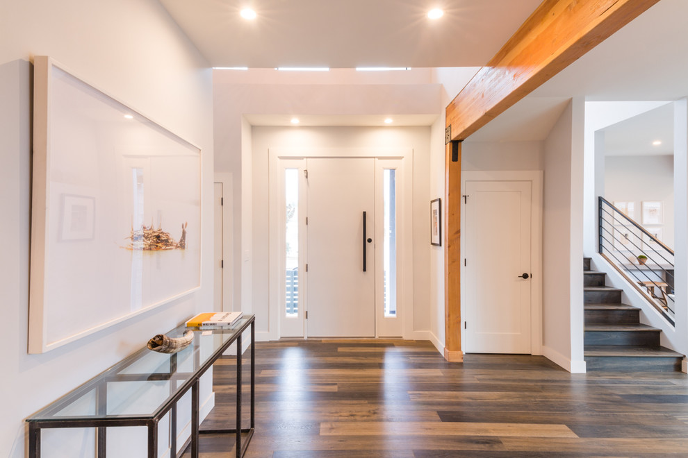 Large minimalist dark wood floor entryway photo in Los Angeles with gray walls and a white front door