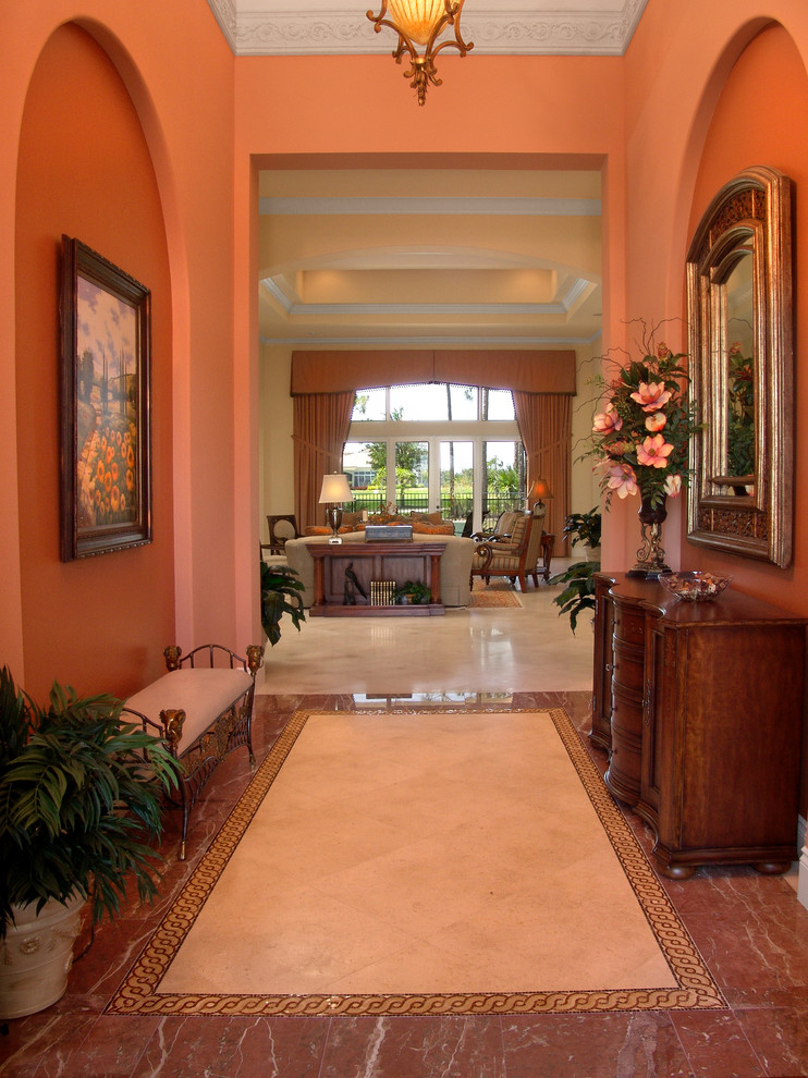 Exempel på en mellanstor klassisk hall, med orange väggar och marmorgolv