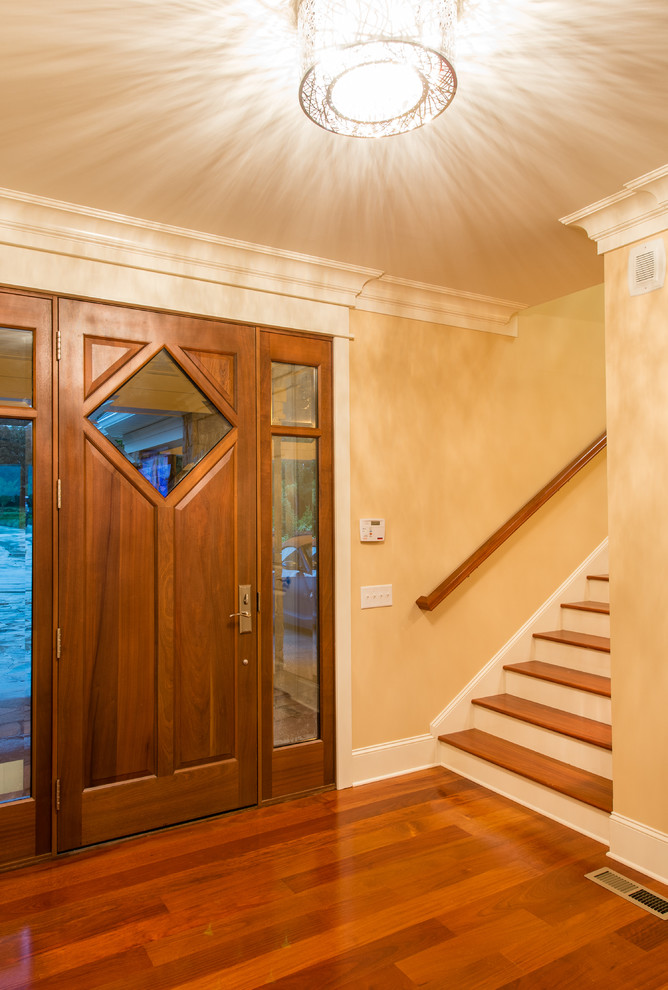 Immagine di una porta d'ingresso design di medie dimensioni con pareti beige, pavimento in legno massello medio, una porta singola e una porta in legno bruno