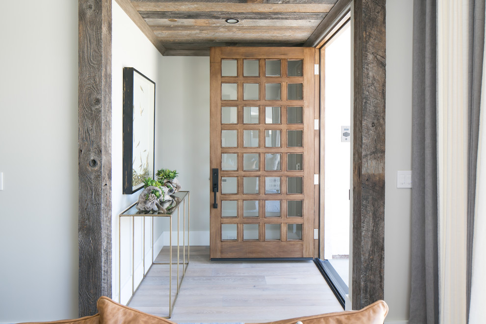Modelo de entrada costera con paredes blancas, suelo de madera en tonos medios, puerta simple y puerta de madera en tonos medios