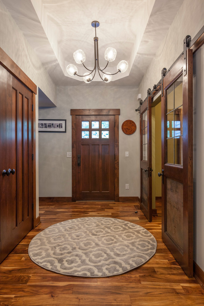 Mittelgroßes Uriges Foyer mit grauer Wandfarbe, braunem Holzboden, Einzeltür und hellbrauner Holzhaustür in Milwaukee