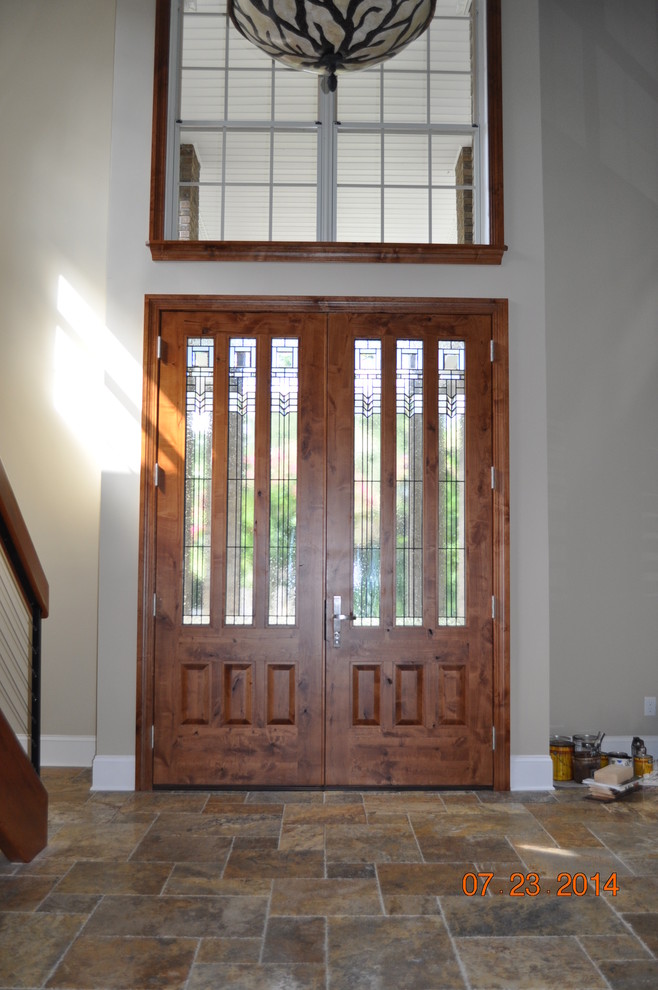 Cette photo montre une entrée tendance avec un mur gris, un sol en ardoise, une porte double et une porte en bois brun.